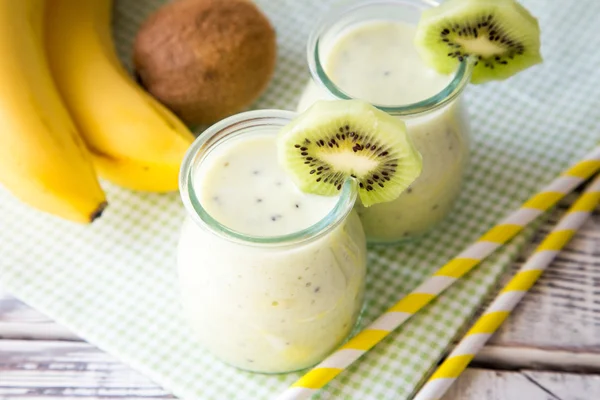 Muz smoothie kivi ve yulaf üzerinde ahşap masa lambası.