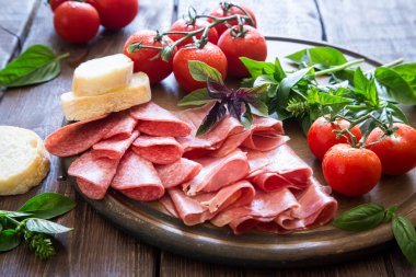 Meze jambon, bresaola ve salam. ekmek, domates ve fesleğen