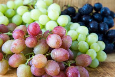 Tahta masadaki üzümler. Beyaz, pembe ve siyah üzümler..