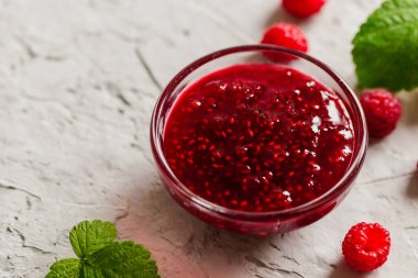 Beton zeminde ev yapımı ahududu reçeli taze ahududu ve seçici bir odak noktası var..