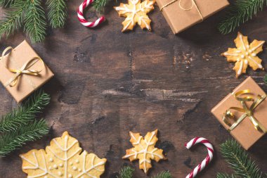 Yılbaşı geçmişi. Köknar dalları, hediyeler, tatlılar, kurabiyeler, tarçınlı karanlık ahşap arka planda Noel kompozisyonu