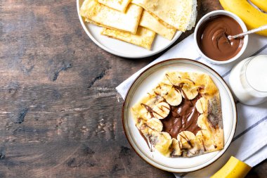 Krep, tabakta ince krepler. Fındıklı çikolata ve muzlu krep tabakta. Lezzetli krep ya da tatlı soslu blini..