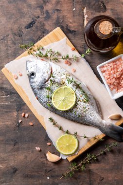 Taze çiğ dorado balığı. Dorado balığı ve yemek malzemeleri - limon, tuz, yağ, sarımsak, kekik ve otlar