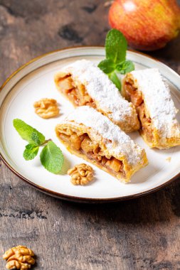 Elma ve tarçınlı ev yapımı meyveli börek ahşap bir arka planda, metin için yeri olan bir tabakta.,