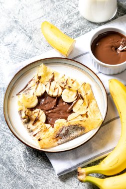 Krep, tabakta ince krepler. Fındıklı çikolata ve muzlu krep tabakta. Lezzetli krep ya da tatlı soslu blini..