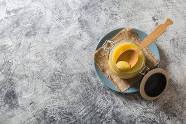 Kavanozda tereyağı ve gri masada tahta kaşık. Üst Manzara. Kopyalama. Ghee yağı sağlıklı yağlıdır ve Hint yemeklerinin çoğunda yaygın bir yemek malzemesidir.