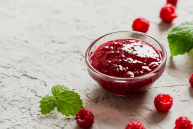 Beton zeminde ev yapımı ahududu reçeli taze ahududu ve seçici bir odak noktası var..