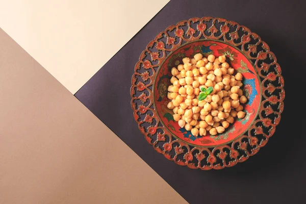 Cooked chick peas in a beautiful authentic plate. Spilled chick peas. Top view
