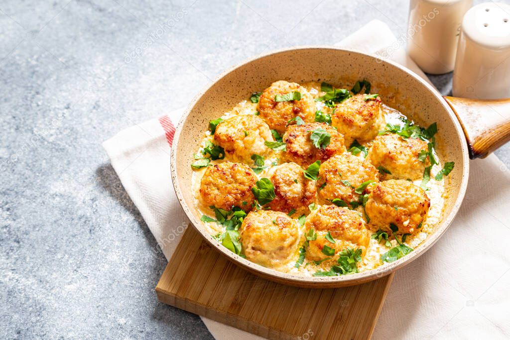 meatballs in white sauce in a frying pan on a gray background, comfortable homemade healthy food
