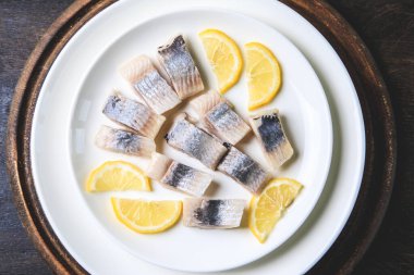 Tabakta limonlu tuzlu ringa balığı ve ahşap zemin üzerinde fotokopi alanı. Salamura edilmiş balık. Sağlıklı doymamış yağlı yiyecekler, Omega 3. Üst manzara, düz uzanma