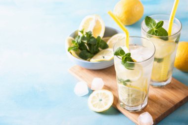 İki bardak limonata ya da naneli mojito kokteyli soğuk, ferahlatıcı içecek ya da buzlu mavi arka plan. Boşluğu kopyala.