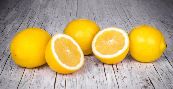Ряд лимонов на деревянном кухонном столе . — стоковое фото