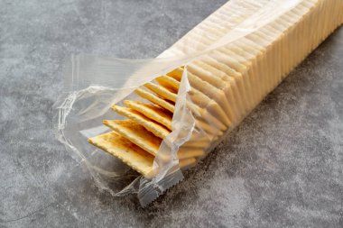 Kısmen açılmış plastik ambalajda tuzsuz krakerler.