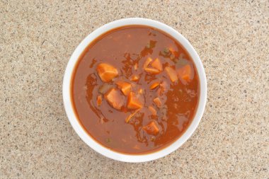 Mutfak tezgahında bir kase sığır eti sebze çorbası, taze malzemeler ve sıcak ev yapımı konforlu yemekler..