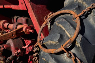 Tarım işlerinde ve zorlu zemin koşullarında sıklıkla kullanılan, daha iyi çekiş için halka zinciri ile donatılmış bir tarım traktör lastiğinin yakın çekimi.