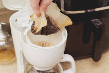 Kahve makinesi sepetinden kullanılmış bir filtreyi atmak.