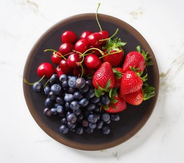 Yukarıdan kase mermer masada yaz meyveleri