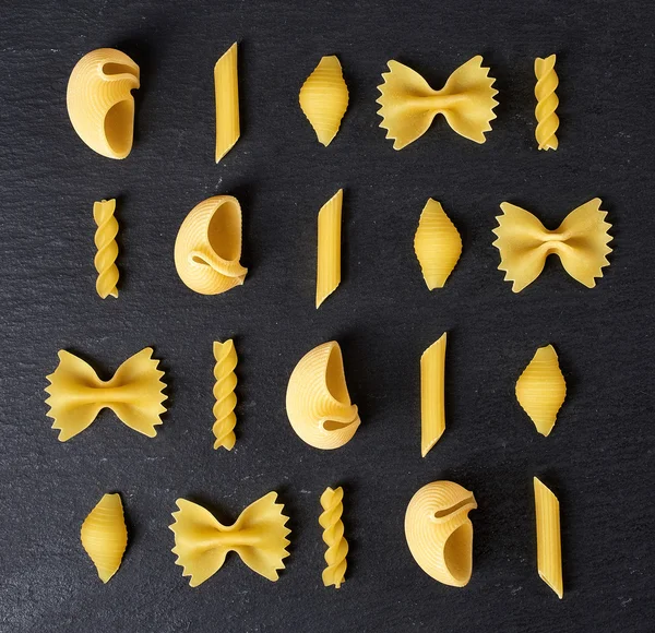 Vari tipi di pasta su fondo nero, dall'alto — Foto Stock