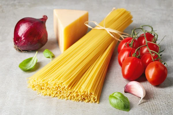 Pasta de espaguetis, queso y verduras sobre una mesa de piedra gris — Foto de Stock