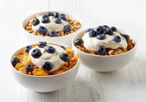 Trei tipuri de cereale cu iaurt și afine pe tabla albă — Fotografie, imagine de stoc