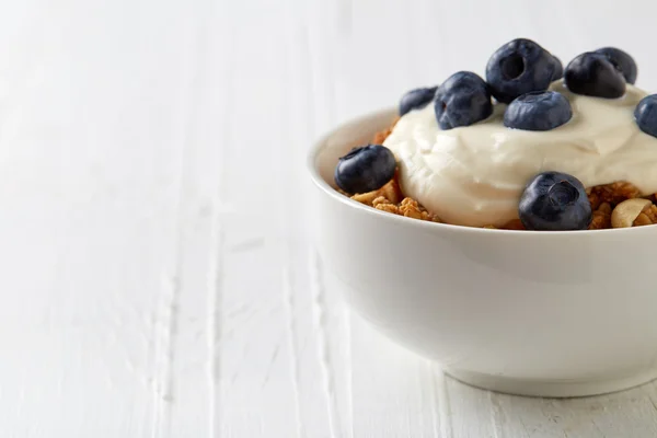 Castron cu muesli de cereale integrale cu afine și iaurt pe alb — Fotografie, imagine de stoc