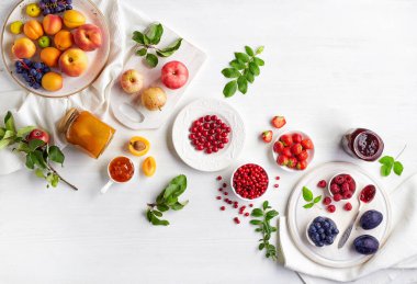 Cam kavanozda ev yapımı reçel, beyaz ahşap masada taze meyve ve böğürtlen.