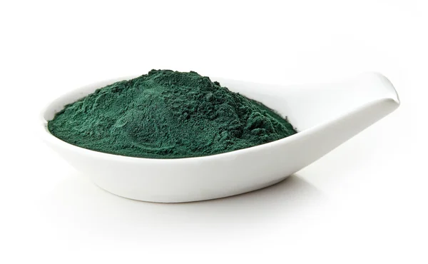 Beyaz arka plan üzerinde beyaz porselen kaşık Spirulina tozu