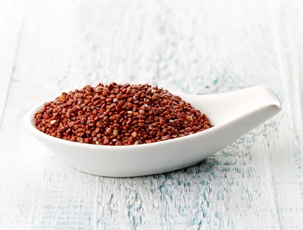 Quinoa vermelha em colher de porcelana branca — Fotografia de Stock