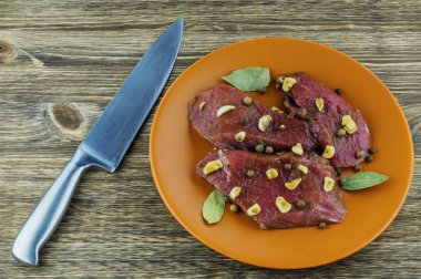 Marine edilmiş sığır eti, baharat, sarımsak ve defne yaprağı üzerinde bir seramik tabak.