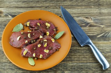 Marine edilmiş sığır eti, baharat, sarımsak ve defne yaprağı üzerinde bir seramik tabak.