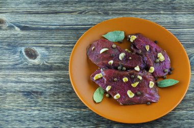 Marine edilmiş sığır eti, baharat, sarımsak ve defne yaprağı üzerinde bir seramik tabak.