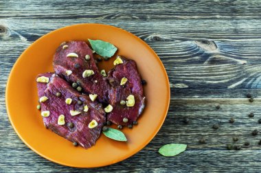 Marine edilmiş sığır eti, baharat, sarımsak ve defne yaprağı üzerinde bir seramik tabak.