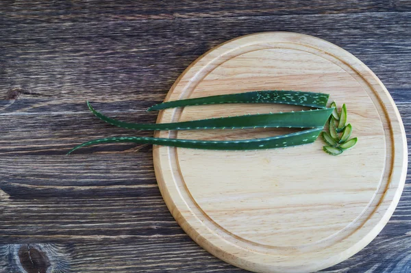 Hoja fresca de aloe vera en la tabla de cortar, sobre fondo de madera . — Foto de Stock