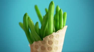 Waffle bardağındaki yeşil fasulyeler mavi arka planda dönüyorlar. Vegan gıda konsepti. Fast food yerine sağlıklı yemek..