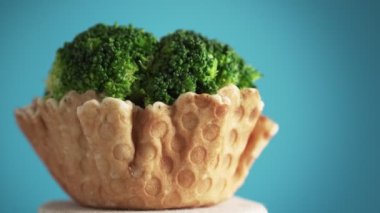 Brokoli, waffle fincanındaki cilt bakımı mavi arka planda döner. Vegan gıda konsepti. Fast food yerine sağlıklı yemek..