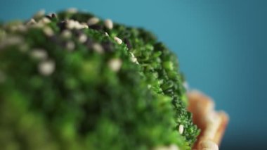 Mavi arka planda siyah ve beyaz susamlı bir waffle kabında brokoli infloresanları, makro çekim. Vegan gıda konsepti. Fast food yerine sağlıklı yemek..