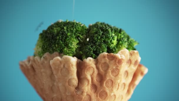黑白相间的芝麻落在美味的西兰花上 花椰菜在华夫饼杯中的花序在蓝色背景上旋转 食物的概念 以健康食品取代快餐 — 图库视频影像
