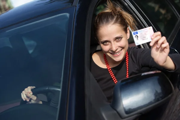 젊은 여 자가 그녀의 드라이버의 라이센스 키를 보여주는 차 뒤에 — 스톡 사진