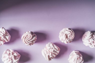 Mor arka planda taze marşmelovlar. Zephyr, kremalı pasta. Ev yemeği konsepti, tatlılar. Minimalizm, üst görünüm, düz görünüm, telif alanı.