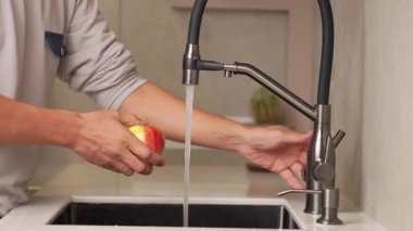 Mutfak lavabosundaki suyun altında elmaları yıkayan tanınmamış kişiler. Taze meyve temizleyen adam. Sağlıklı yaşam tarzı kavramı.