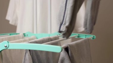 Yumuşak kumaş giysiler parlak ve kapalı alandaki kurutma askısına tutunur. Tanınmayan kişi kuruması için kıyafet asıyor.