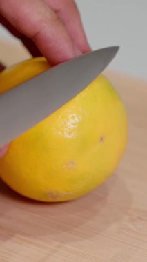 Makro, olgun limonu mutfak bıçağıyla kesme sahnesi. Detaylı narenciye dokusu, içecekler, yemek pişirme ve sağlık konseptleri için taze malzemeler. Sosyal medya makaraları, hikâyeler, şortlar için ideal