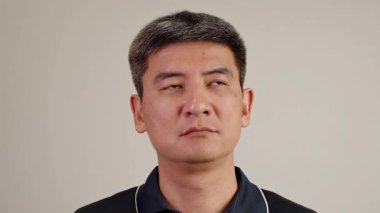 Asyalı bir adamın düşüncelere dalmışken yanağına dokunuşunun yakın plan portresi. Karar verme, fikirler, odaklanma, problem çözme, yansıtma ve zihin yapısı temaları için mükemmel.