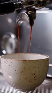 Portafilterden seramik kaba akan zengin espresso akıntıları. Modern kahve dükkanında krema ve çıkartma işleminin yakın plan detayları. Kahveci eğitimi görsellerinin dikey videosu.