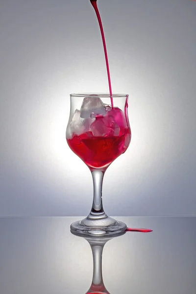 Pouring red syrup on ice with gray background. — Stock Photo, Image