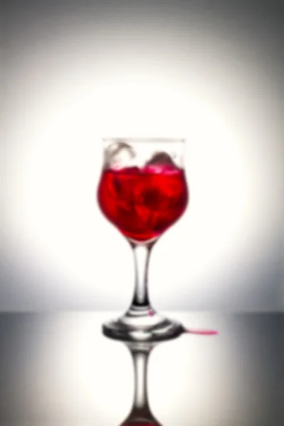 Blurred of red syrup on ice with gray background.