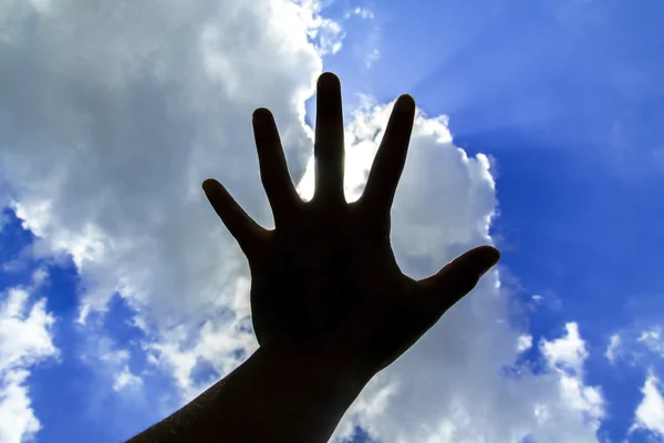 Silhouette of hand reach to the sky with clouds background.