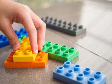 Asya çocuğun el oyun plastik bloklar, closeup bulmaca