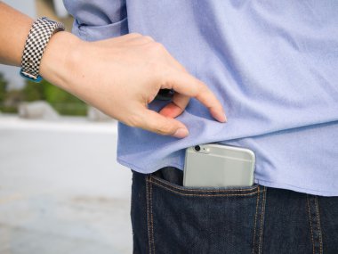 Mavi je arka cebinde bir akıllı telefon çalmaya çalışan bir adam