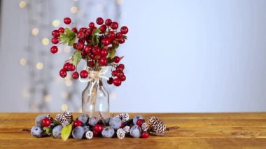 Xmas 'larınız neşeli ve dutlu olsun! Neşeli bir atmosfer için yanıp sönen ışıklar. Kutsal böğürtlenler, kış renkleri ve ahşap bir masanın üzerindeki küçük kozalaklar büyüleyici doğal dokunuşlarıyla ruhu sakinleştirir..